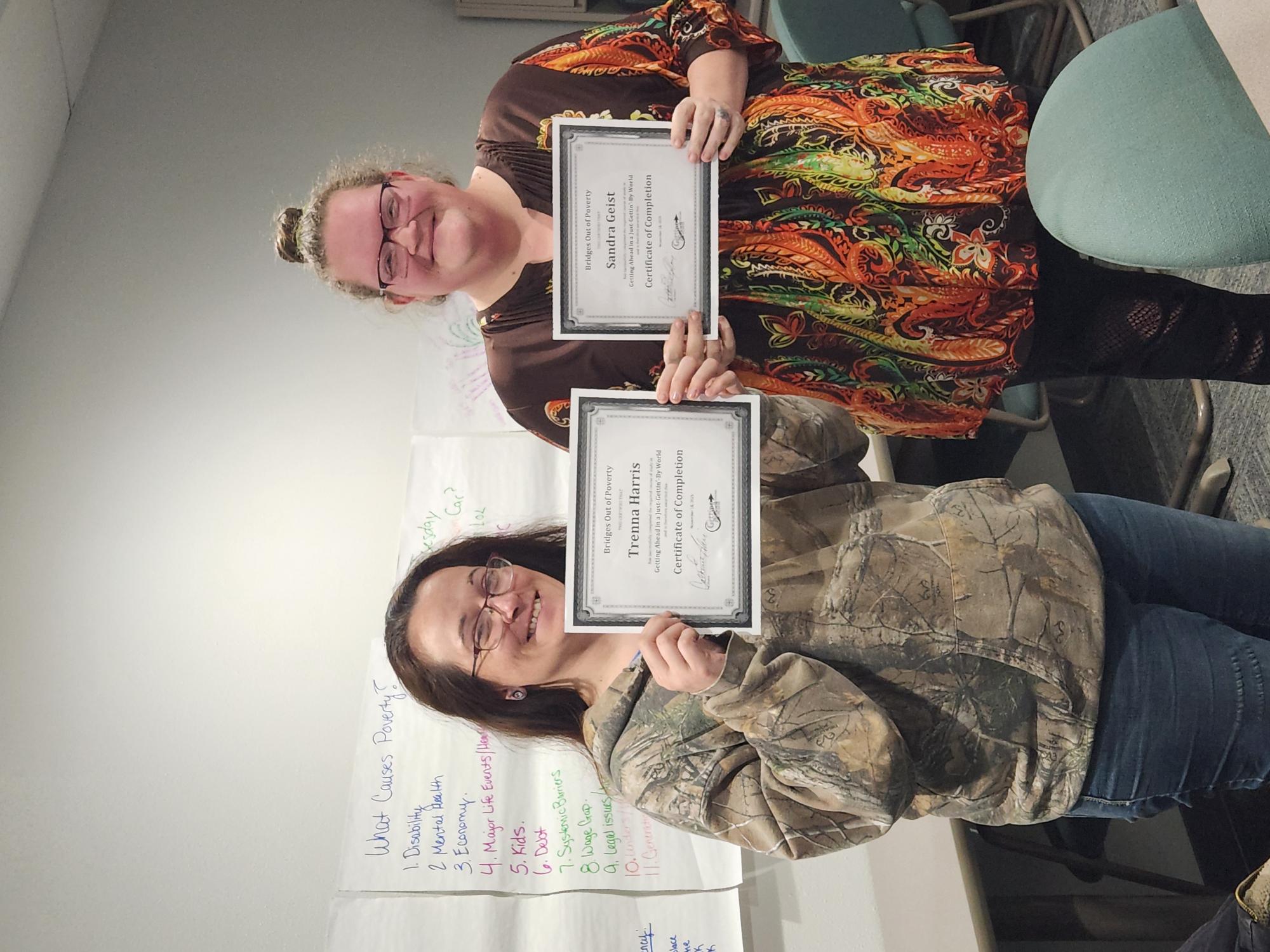 Two women display certificates for program completion.