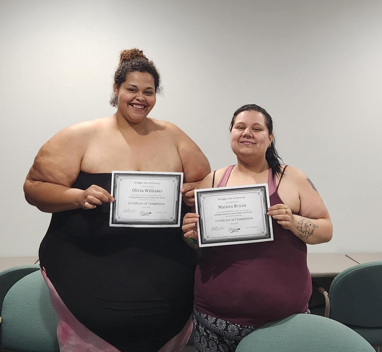 Two women display certificates for program completion.