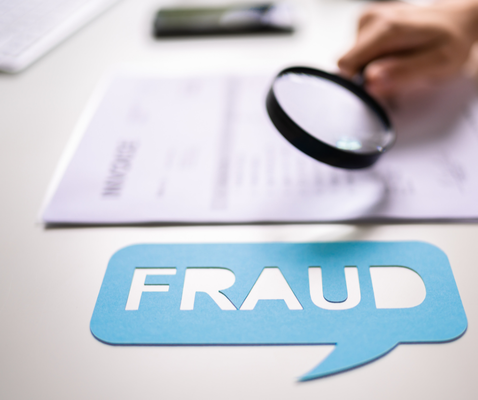 Hand with magnifying glass looking at document on table with blue bubble that reads fraud.